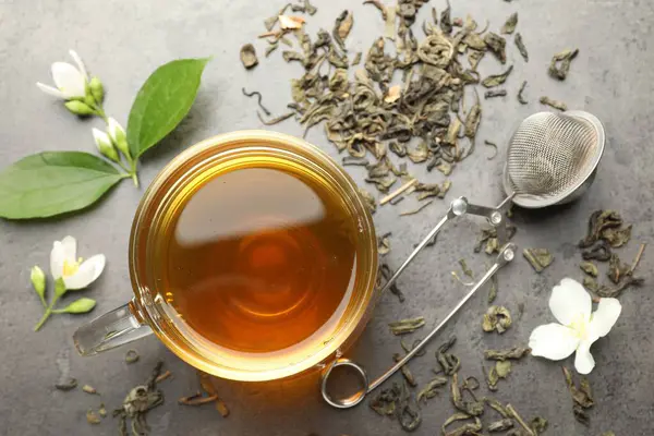 Cam bardakta Aromatik yasemin çayı, Gri masada bira ve çiçekler, düz uzanmış