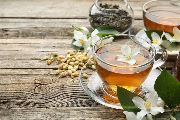Cam bardaklarda yasemin çayı, ahşap masada bira ve çiçekler, yakın plan. Metin için boşluk