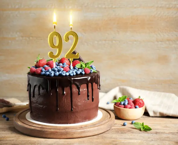 Böğürtlenli çikolatalı kek ve ahşap masada yanan mumlar. Mesaj için yer var. 92. Doğum günü veya başka özel bir gün.