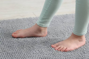 Evdeki yumuşak halıdaki kız, yakın plan.