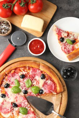 Lezzetli pizza ve malzemeler gri masada, düz yatıyordu.