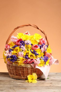 Tahta masada mercan zemin üzerinde güzel çiçeklerle dolu bir sepet.