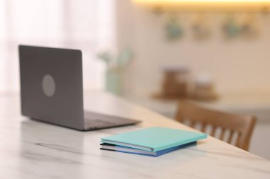 Mutfaktaki beyaz mermer masaya dizilmiş defterler ve dizüstü bilgisayarlar, seçici odaklanma