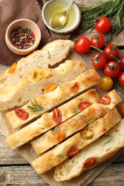 Domatesli, baharatlı ve yağlı nefis Focaccia 'yı ahşap masaya koyun.