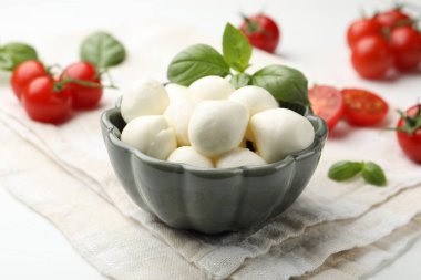 Lezzetli mozzarella peynir topları, domates ve fesleğen beyaz ahşap masada, yakın plan.