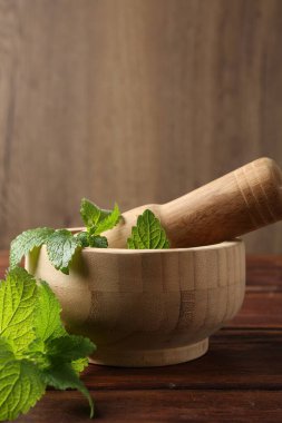 Taze limon merhemi yaprakları, ahşap masada tokmak ve havan topu, yakın plan. Metin için boşluk