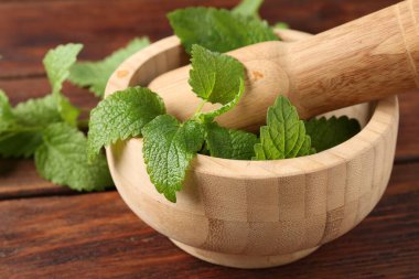 Taze limon merhemi yaprakları, ahşap masada tokmak ve havan topu, yakın plan.