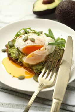 Avokadolu lezzetli sandviç, haşlanmış yumurta, roka ve balkabağı masada servis ediliyor, yakın plan.
