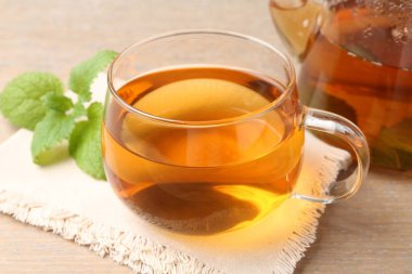Cam fincanda aromatik limon merhemi çayı, çaydanlık ve ahşap masada taze yapraklar, yakın plan.