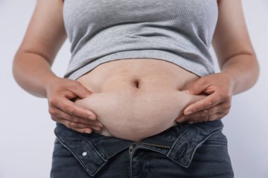 Hafif arka planda aşırı göbek yağı olan kadın, yakın plan. Aşırı kilolu