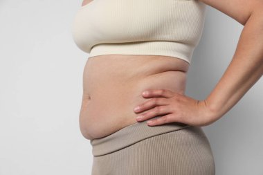 Hafif arka planda aşırı göbek yağı olan kadın, yakın plan. Aşırı kilolu