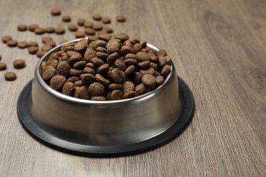 Tahta arka planda besleme kabında kurutulmuş hayvan mamaları, yakın plan.