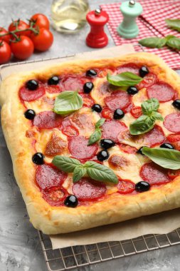 Lezzetli ev yapımı pizza ve malzemeler gri masada, yakın plan.