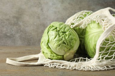Taze lahanalar ve ahşap masada ağ torba, yakın plan. Metin için boşluk