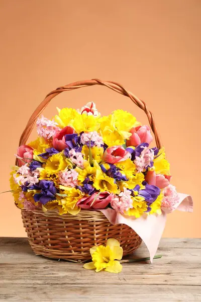 Tahta masada mercan zemin üzerinde güzel çiçeklerle dolu bir sepet.