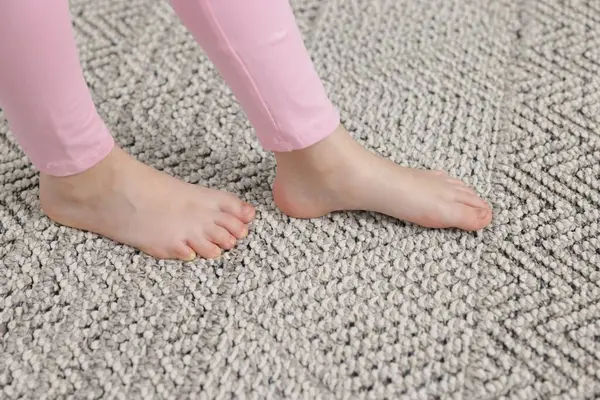 Evdeki gri halıda yürüyen kız, yakın plan.