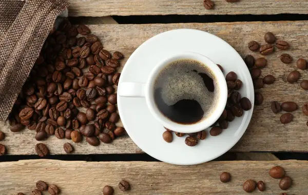 Aromatik kahve fincanda ve fasulye ahşap masada, düz yerde.
