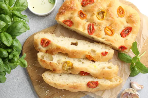Domatesli, baharatlı ve yağlı nefis Focaccia 'yı gri masaya koyun.