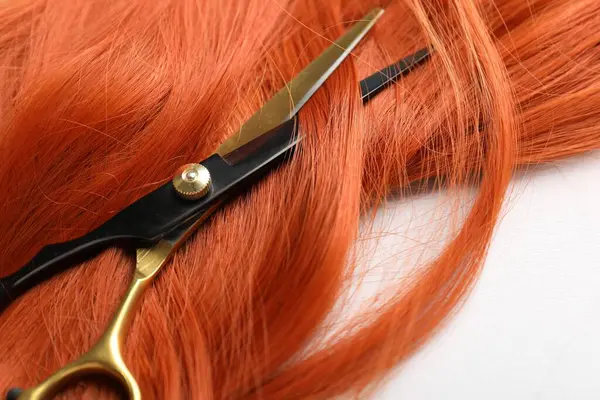 Hafif arkaplanda saç teli ve makas, yakın plan.