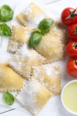 Pişmemiş ravioli, fesleğen, domates ve yağ beyaz ahşap masa üzerinde, düz uzanmış