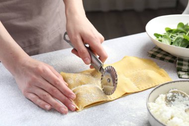 Işık masasında ravioli kesen kadın, yakın plan.