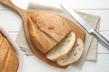 Beyaz ahşap masada ekmek ve bıçak kes, düz uzan.