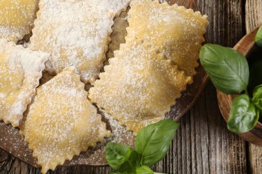 Ahşap masada pişmemiş ravioli ve fesleğen, yakın plan.