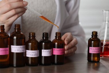 Laboratuardaki ahşap masada lüks parfüm üreten profesyonel parfümcü.