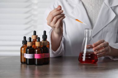 Laboratuardaki ahşap masada lüks parfüm üreten profesyonel parfümcü.