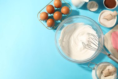Açık mavi masada çırpılmış krema, yumurta ve diğer ürünlerle çırpın. Metin için boşluk