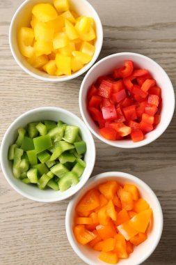 Taze renkli dolmalık biberler ahşap masadaki kaselerde, düz yatıyordu.