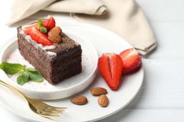 Çilekli, bademli ve beyaz ahşap masadaki nane şekerli lezzetli çikolatalı pasta.