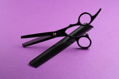 Makas ve tarak menekşe arkaplanda, yakın plan. Kuaför aletleri