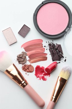 Beyaz arka planda farklı kozmetik ürünler ve makyaj fırçaları, düz yatış