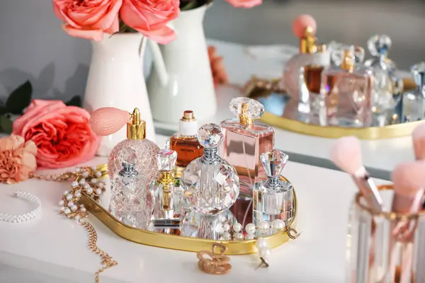 Farklı parfüm şişeleri, aksesuarlar ve çiçekler kapalı salonda.