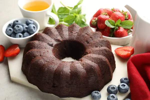 Lezzetli çikolatalı kek, çay ve böğürtlen ışık masasında, yakın plan.