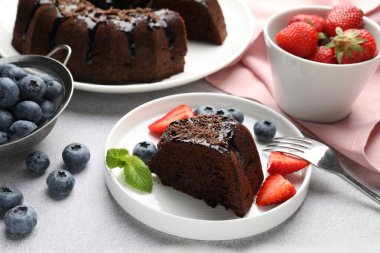 Açık gri desenli masada çilekli, nane ve yaban mersinli çikolatalı kek, yakın plan.