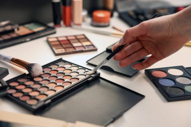 Makyaj masasında fırça ve göz falı olan kadın, yakın plan.