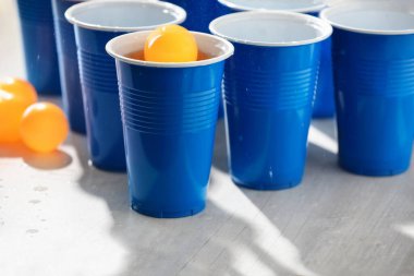 Plastik bardaklar, alkollü içecekler ve açık ahşap masada toplar, yakın plan. Bira pong oyunu