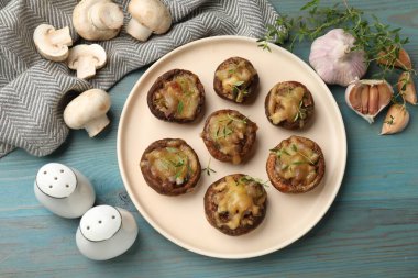 Eritilmiş peynirli lezzetli mantarlar, kekik ve baharatlar açık mavi ahşap masa, düz uzanmış