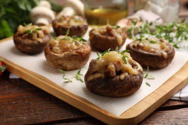 Eritilmiş peynirli lezzetli mantarlar ve ahşap masadaki kekik, yakın plan.