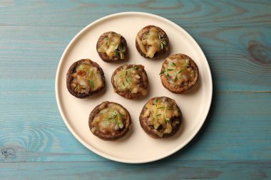 Eritilmiş peynirli lezzetli mantarlar ve açık mavi ahşap masa üzerinde kekik.