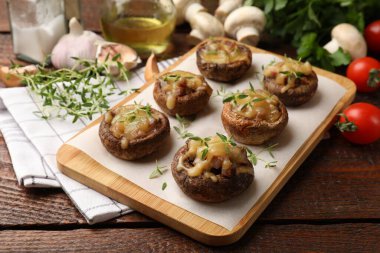 Eritilmiş peynirli lezzetli mantarlar ve ahşap masadaki kekik, yakın plan.