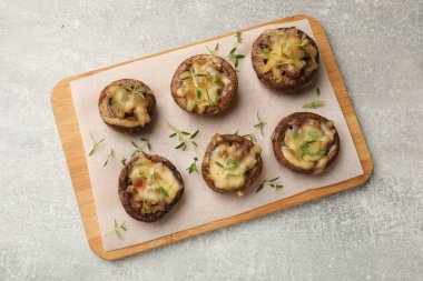 Eritilmiş peynirli lezzetli mantarlar ve gri desenli masa üzerinde kekik.