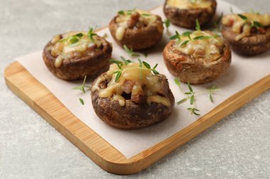 Eritilmiş peynirli lezzetli mantarlar ve gri desenli masadaki kekik, yakın plan.