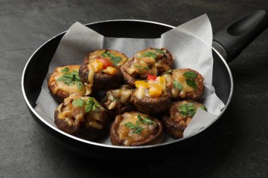 Kızartma tavasında lezzetli mantarlar, siyah masada, yakın plan.