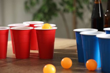 Bira pong oyunu. İçkili plastik bardaklar ve toplar ahşap masada, yakın plan.