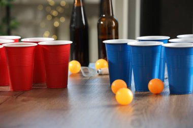 Bira pong oyunu. İçkili plastik bardaklar ve toplar ahşap masada, yakın plan.