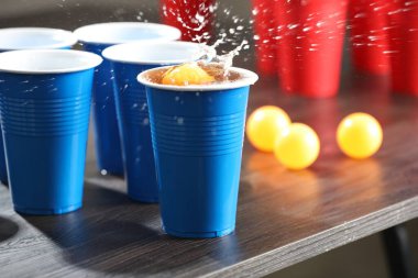 Bira pong oyunu. İçkili plastik bardaklar ve toplar ahşap masada, yakın plan. Metin için boşluk