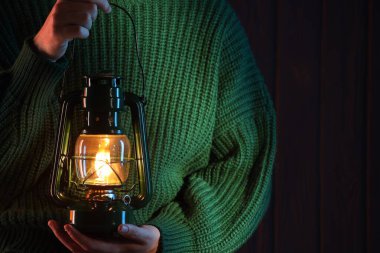 Ahşap duvarın yanında eski model gaz lambası tutan kadın, yakın plan. Metin için boşluk